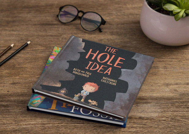 Prestige Publishings children's book mockup for "The Hole Idea" on a wooden desk.