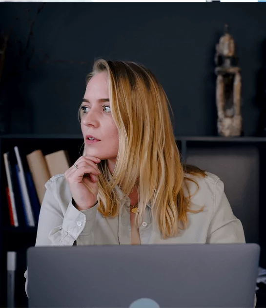 A thoughtful woman sitting at a laptop, representing expert manuscript critique and author consultation.