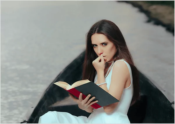 A woman in a white dress sitting in a boat and reading a red book, symbolizing romantic fiction publishing and creative storytelling.