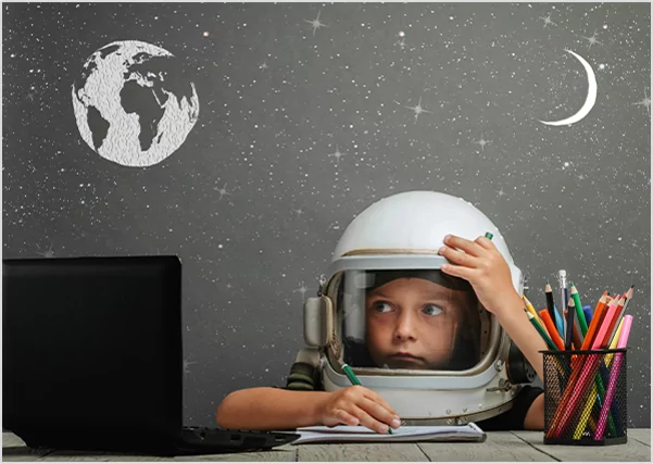 Child in an astronaut helmet at a desk.