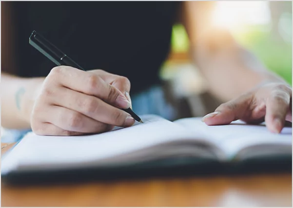 A person holding a pencil while checking a printed manuscript against a digital tablet, representing professional editorial verification and cross-platform publishing quality control.