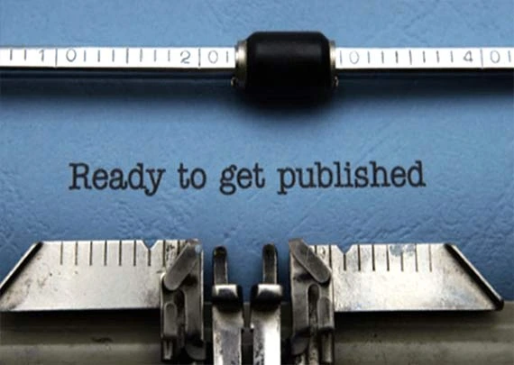 Hands typing on a laptop at a wooden table with notebooks, representing professional ghostwriting and book editing services.