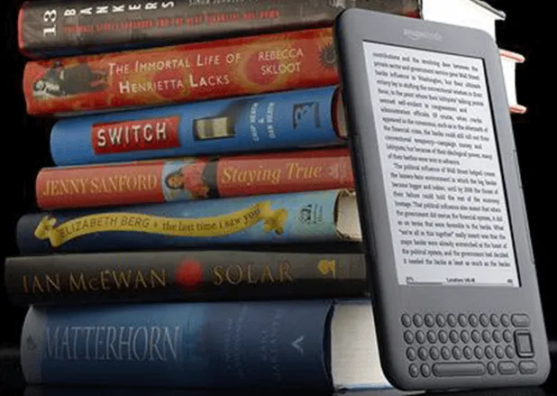 An e-reader showing a page of text leaning against a tall stack of physical books, representing digital ebook conversion and traditional print publishing services.