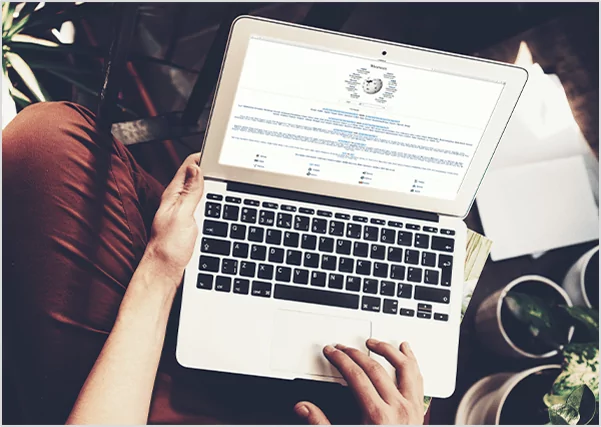 A person using a laptop to view the multilingual landing page of Wikipedia while sitting in a relaxed environment.