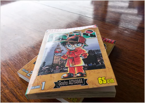 Close-up of Volume 1 of the "Detective Conan" (Case Closed) manga series by Gosho Aoyama resting on a wooden table, representing specialized manga publishing and Japanese graphic novel translation services.