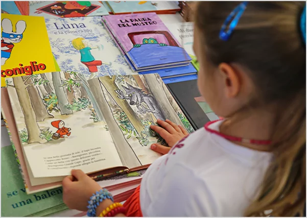 A young girl looking at an illustrated book of a wolf in the woods, representing children's book illustration and narrative development services.