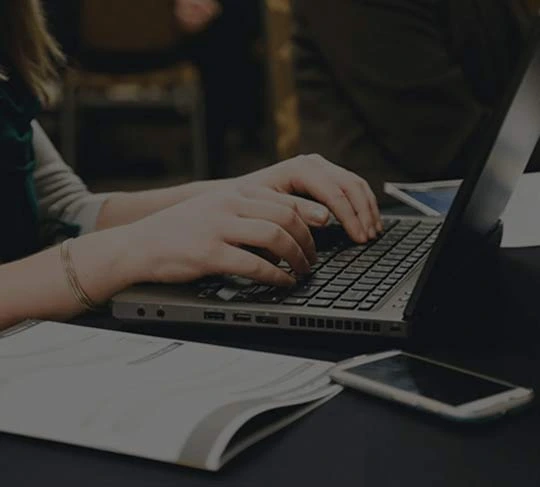 Typing on a laptop at a wooden table, representing professional ghostwriting